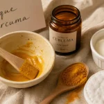 Curcuma bienfaits sur la peau : masque visage au curcuma, poudre et crème sur tissu beige